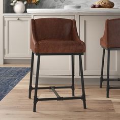 two brown leather bar stools sitting in front of a counter