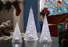 three clear plastic christmas trees sitting on top of a table next to a box of presents