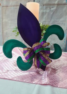 a purple and green flower sitting on top of a table next to a lit candle