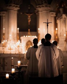 two men standing in front of a cross with candles around them and the back of their backs