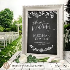 a chalkboard sign with white flowers and greenery is displayed in front of an outdoor ceremony