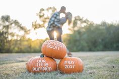 three pumpkins with the words our little pumpkin written on them in front of a man