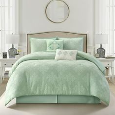 a bed with green comforters and pillows in a room