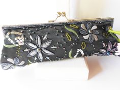 "This vintage black evening bag is beaded and embroidered. The vintage bead bag has a background of black taffeta. The front and back are covered with beading and embroidery in grey and green. The bag has a silvertone frame and a kiss lock. This is a bag that would be gorgeous for evening and would look stunning with a great pair of jeans. The interior of the bag is black taffeta and it contains one pocket. This is a beaded clutch bag plus it has a chain strap (45\") that can be worn on the shou Embroidered Black Evening Bag For Events, Black Embroidered Evening Bag For Events, Black Beaded Evening Bag For Wedding, Formal Black Embroidered Evening Bag, Black Embellished Evening Bag, Handmade Black Evening Bag For Wedding, Embroidery Clutch, Black Clutch Bag, Holiday Handbag