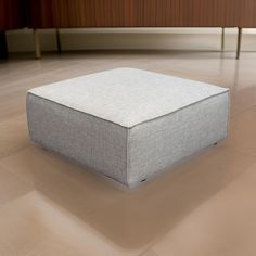 a square ottoman sitting on top of a hard wood floor