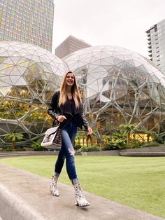 a woman is standing on the edge of a wall in front of some glass domes