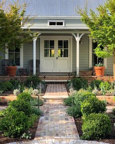 a small house with a white front door and brick walkway leading to the front door