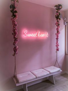 a pink room with flowers hanging from the ceiling and a neon sign that says sweet heart