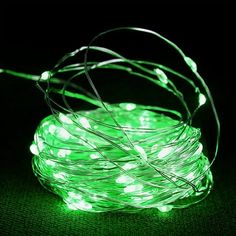 green fairy lights on a black surface with the wire wrapped around it and some white lights