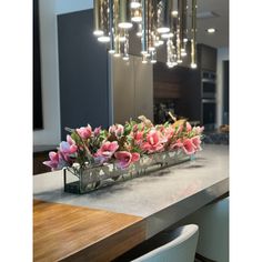 a table with flowers on it in front of a chandelier hanging from the ceiling