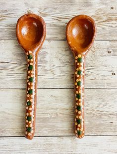 two wooden spoons with beaded designs on them, one is brown and the other is green