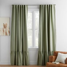 a living room with green curtains and a brown chair