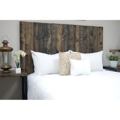 a bed with white pillows and wooden headboard