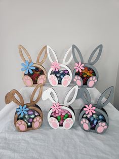 several wooden bunny ears with flowers and candy in them on a white sheeted surface