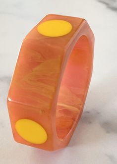 Delicious Octagonal vintage Marblette Bakelite bracelet, 4 dots alternate with plain facets on this large bracelet. Bracelet measures 1 One full inch wide and is .25 inch thick. Beautiful translucent Guava or Melon colored swirl with creamy corn .75 inch dots. The bracelet is in very good vintage condition, sold as found. Incredible statement set, true vintage. Standard 2.5 inch opening. Wide bracelet, as stated one full inch wide. You will not be disappointed with this beauty, it can hold its o Modern Yellow Bangle Bracelets, Modern Orange Bangle Bracelets, Retro Yellow Bangle Bracelet, Retro Yellow Bangle Bracelets, Bakelite Bracelets, Creamy Corn, Bakelite Jewelry, Large Bracelet, Color Swirl