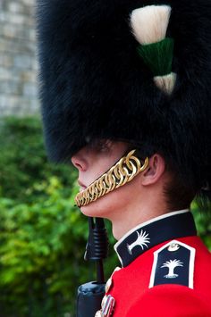 a man in a red uniform with a black and white hat on his head is holding a pipe