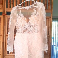 a white wedding dress hanging on a wooden hanger