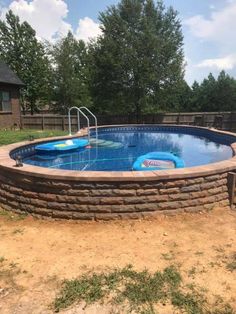 an above ground swimming pool in the middle of a yard with a brick wall around it