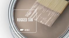 a paint can with a brush in it and the words rugged tan on top