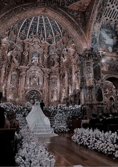 the bride is walking down the aisle in her wedding dress at the alter, surrounded by white flowers