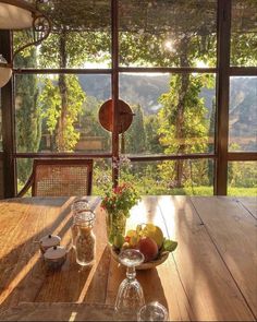 a wooden table topped with fruit on top of a wooden floor next to a window