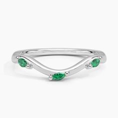 a white gold ring with three green stones on the side and two diamonds in the middle