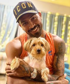 a man in an orange shirt holding a small dog