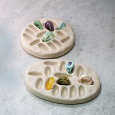 two ceramic trays with stones on them sitting on a counter top next to each other