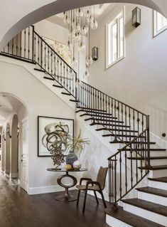 an elegant staircase with chandelier and art on the wall in this home's entryway