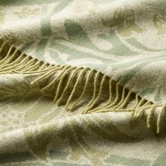 a green and white blanket with fringes on it