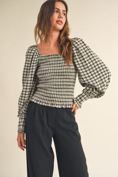 a woman wearing black and white checkered top with puff sleeves, wide legged pants and heels