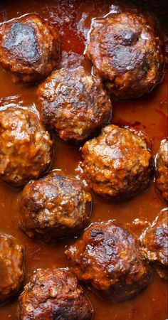 some meatballs are cooking in a red sauce