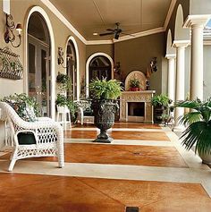 a large porch with white wicker furniture and potted plants