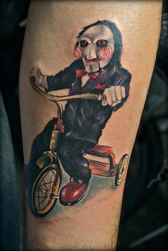 a creepy clown riding a tricycle tattoo on the leg