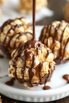 chocolate caramel popcorn balls on a white plate drizzled with melted chocolate