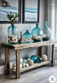 a wooden table topped with vases filled with water and rocks next to a window