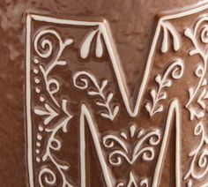 the letter m is made up of chocolate and decorated with swirly designs on it