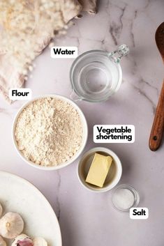 ingredients needed to make garlic bread laid out on a marble counter top, including flour, butter, salt and pepper