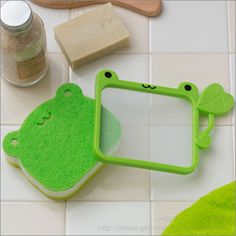 a green frog shaped mirror sitting on top of a white tile floor next to other items