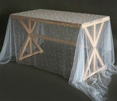 a table covered in white polka dots with a wooden cross on the top and a net covering over it