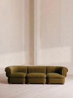 a green couch sitting on top of a wooden floor next to a white wall in a room