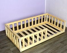 a wooden bed frame sitting on top of a hard wood floor next to a purple wall