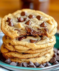 chocolate chip cookies stacked on top of each other in front of a plate with chocolate chips