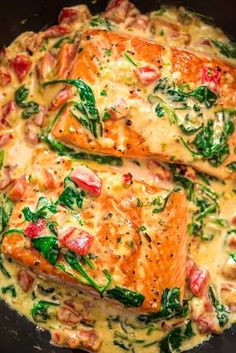 two cooked salmons with spinach and cheese in a skillet