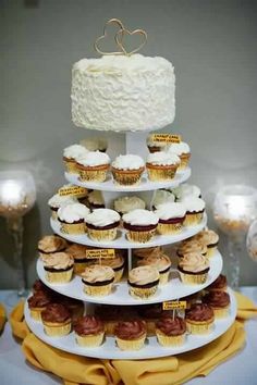 a tiered cake with cupcakes on it