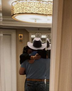 a man taking a selfie in front of a mirror wearing a hat and jeans