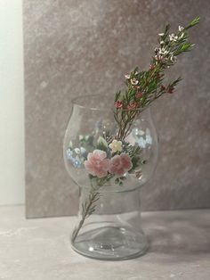 a glass vase with flowers in it sitting on a counter top next to a wall