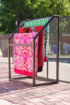 two towels are hanging on a rack near a swimming pool in the summertime time