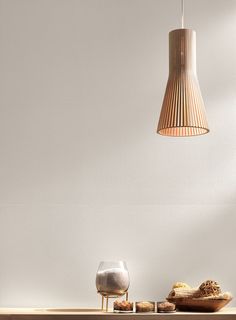 a wooden table topped with food and a light hanging from it's ceiling over it