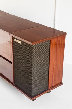 an old fashioned radio sitting on top of a wooden cabinet next to a white wall